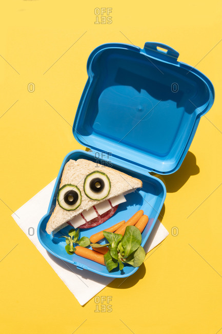 Lunch box with baby carrots and funny looking sandwich with anthropomorphic face