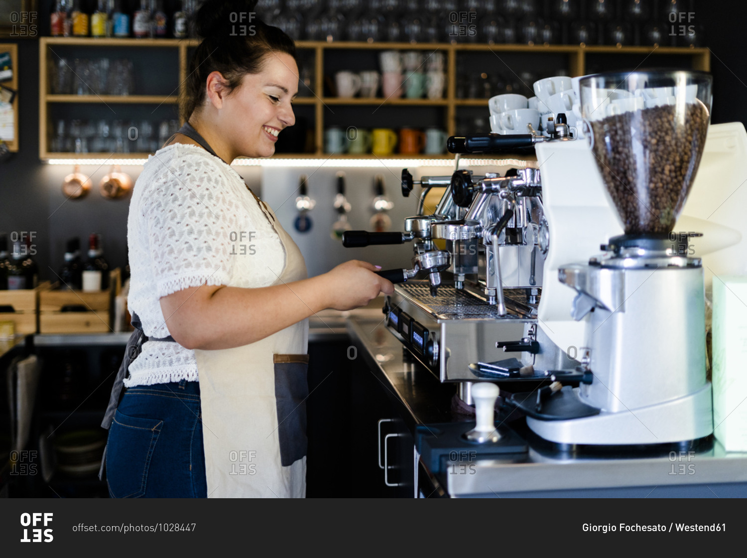 Smiling female barista making coffee through machine in cafe