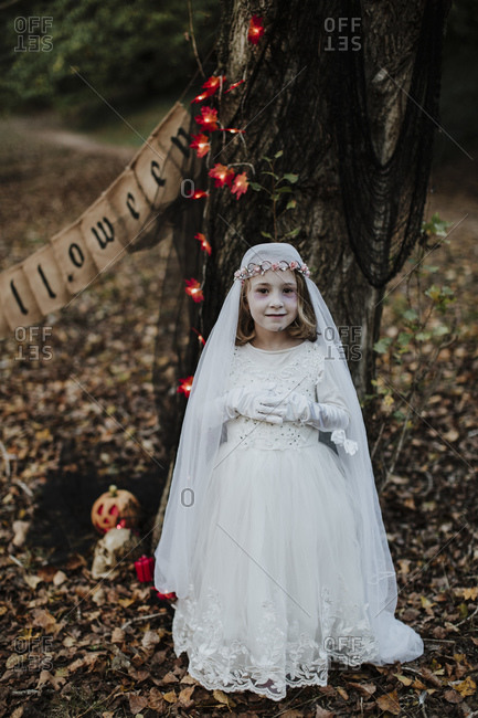 Little girl standing while wearing corpse bride costume against tree in forest