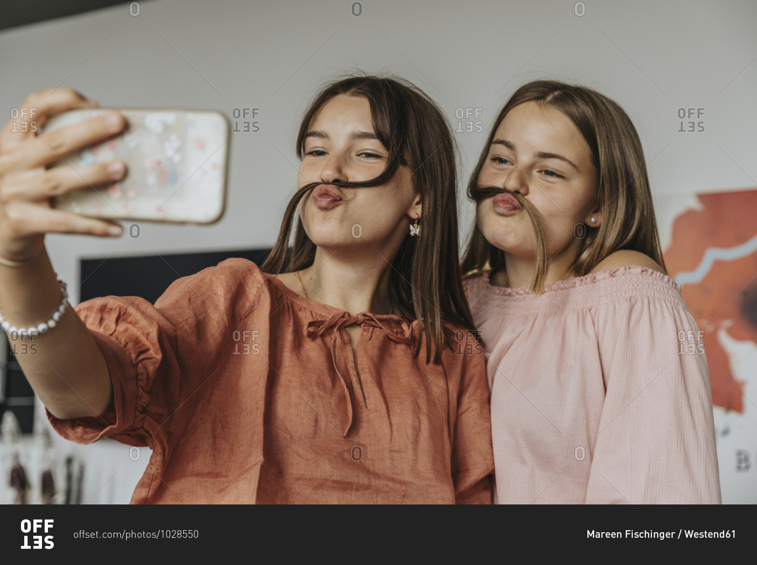 Friends making fake mustache with hair while taking selfie at home