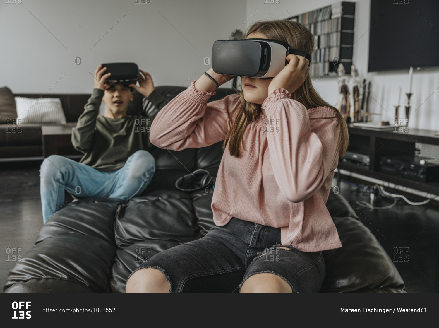 Friends looking through virtual reality simulators while sitting on couch at home
