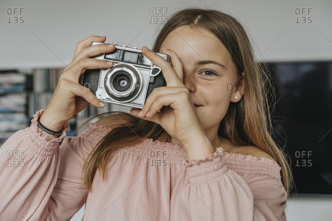 Close-up of girl photographing with old camera at home