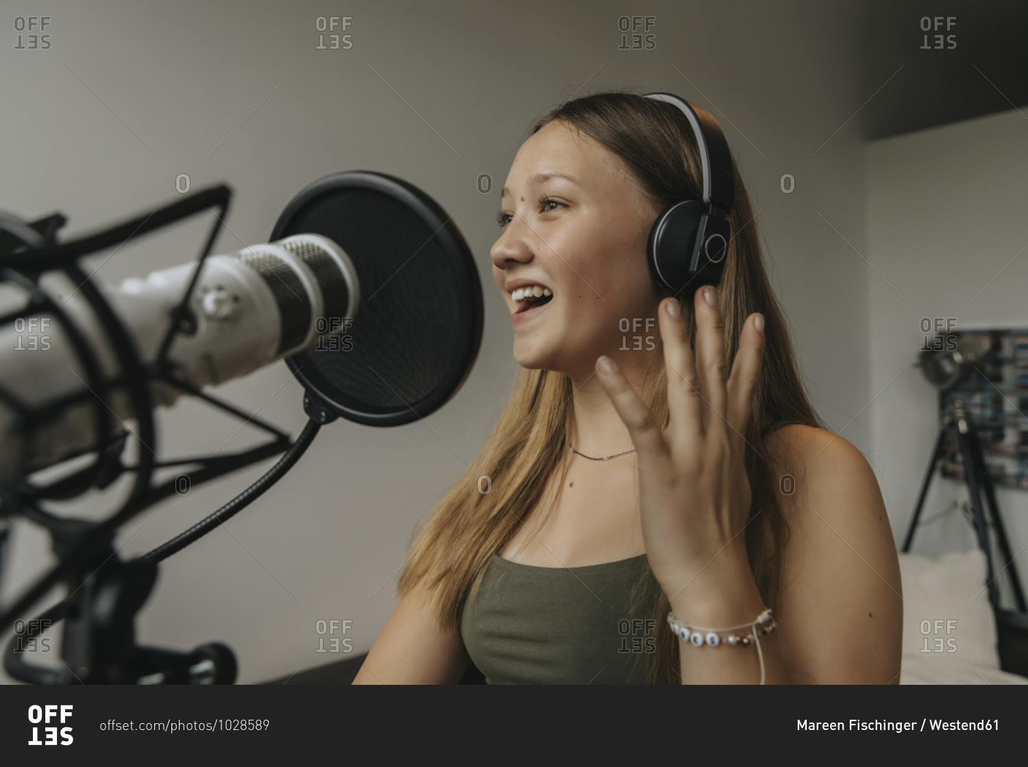 Close-up of happy teenage girl singing against wall in recording studio