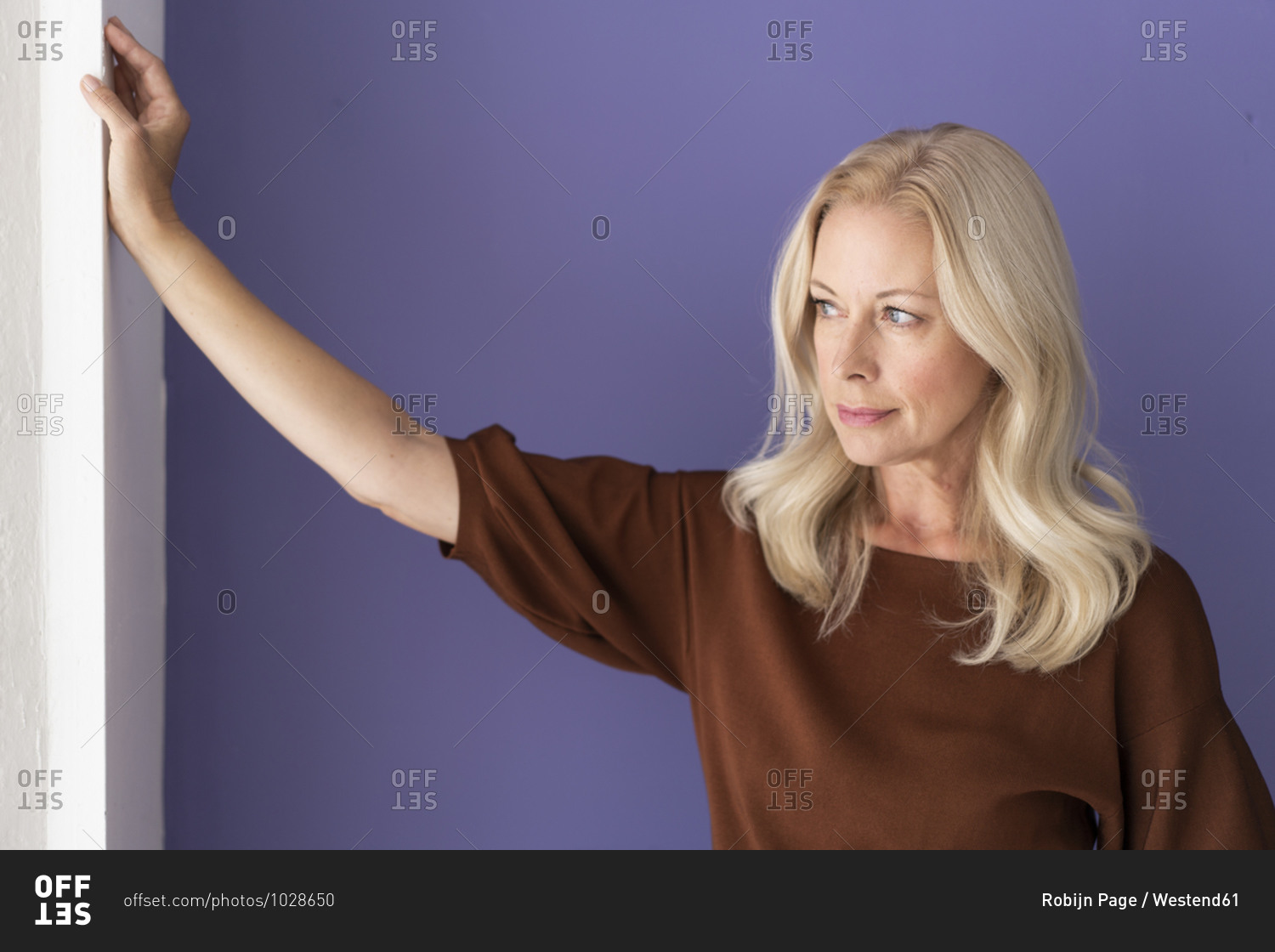 Thoughtful female entrepreneur standing against purple wall in office