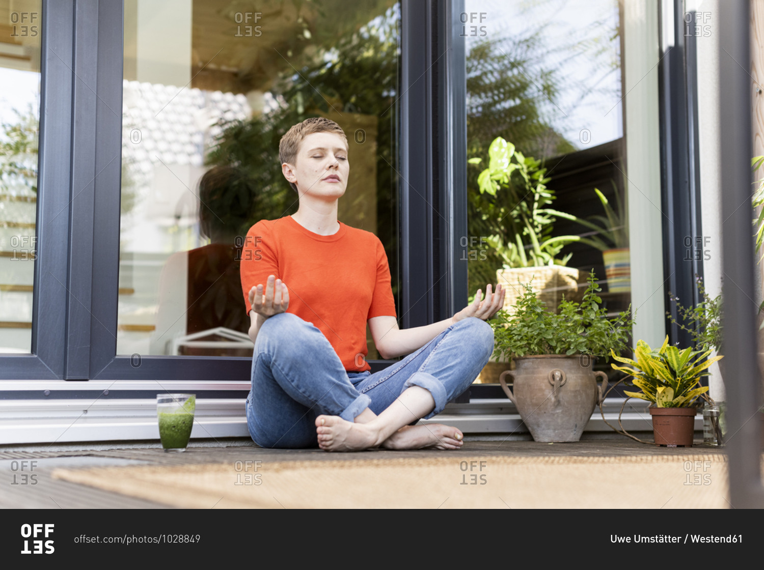 Mid adult woman meditating while sitting against house in porch