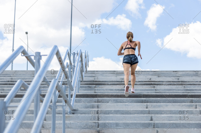 Unrecognizable woman training to climb stairs outdoors, back view
