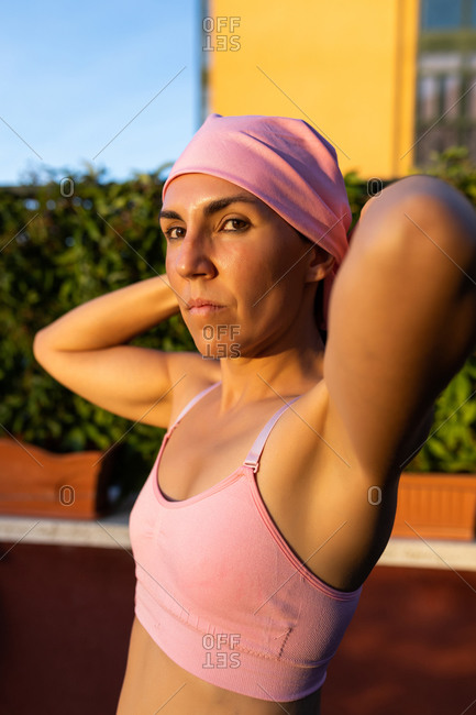 Young brunette woman stretching after training wearing the pink headscarf, symbol of a woman's fight against breast cancer.