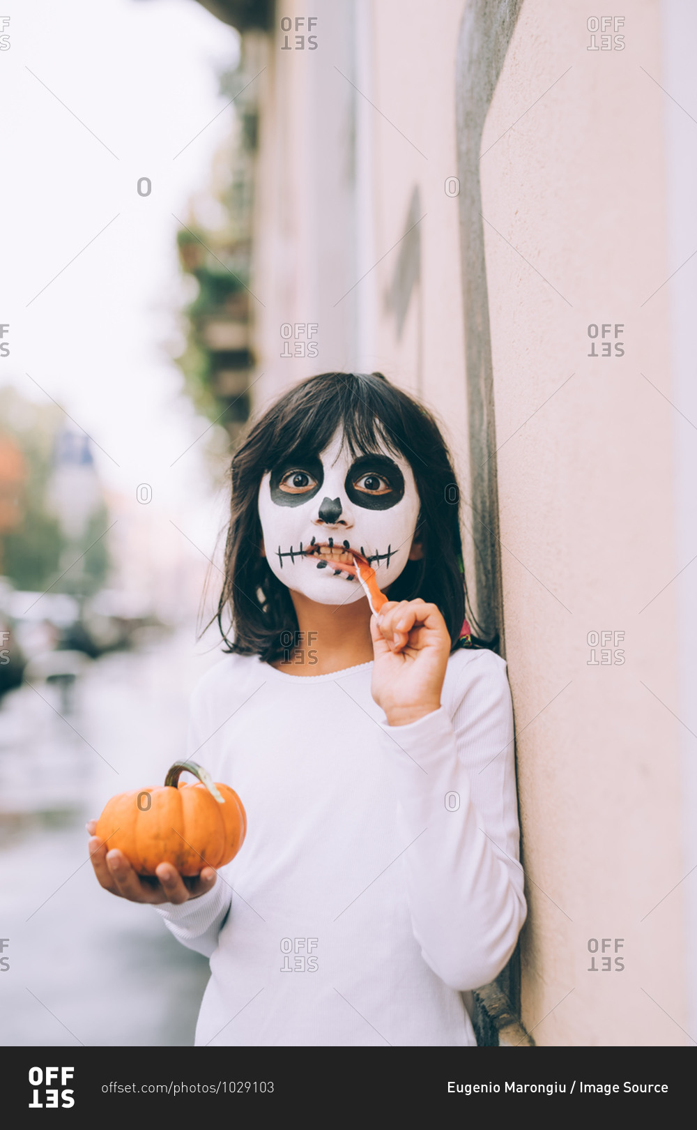 Girl with face paint, eating Halloween candy