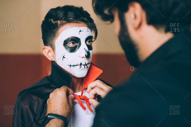 Father adjusting son\'s Halloween costume