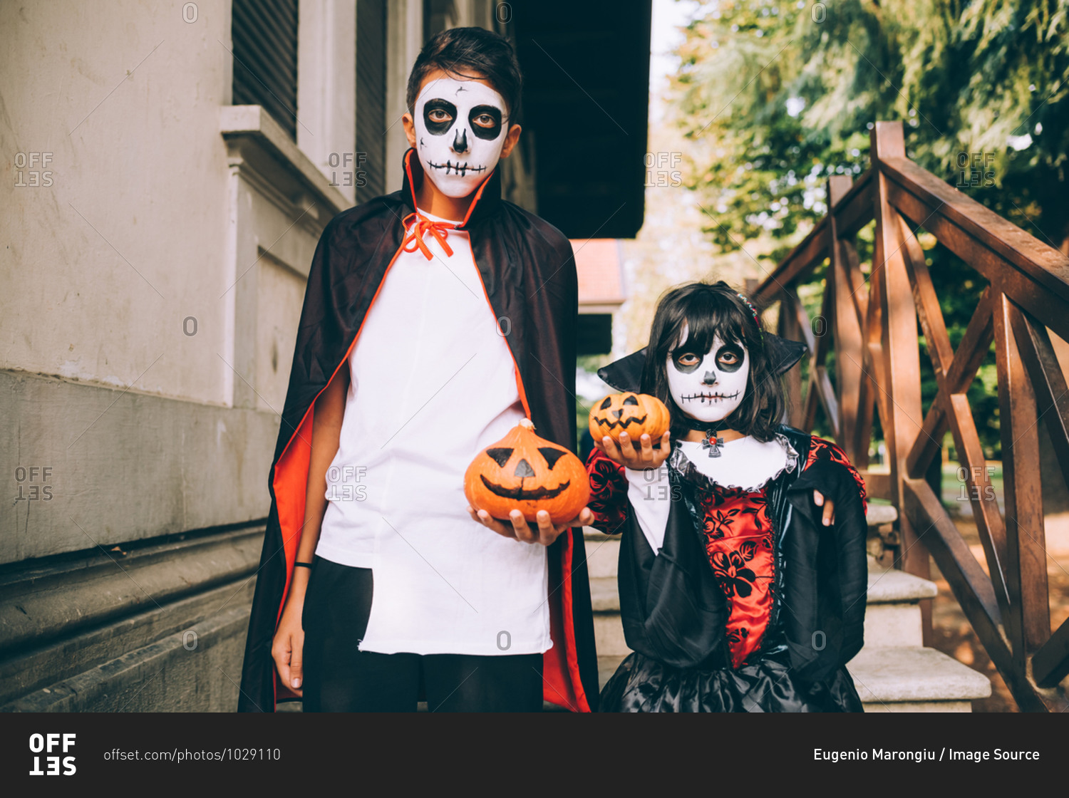 Brother and sister in Halloween costumes with pumpkins