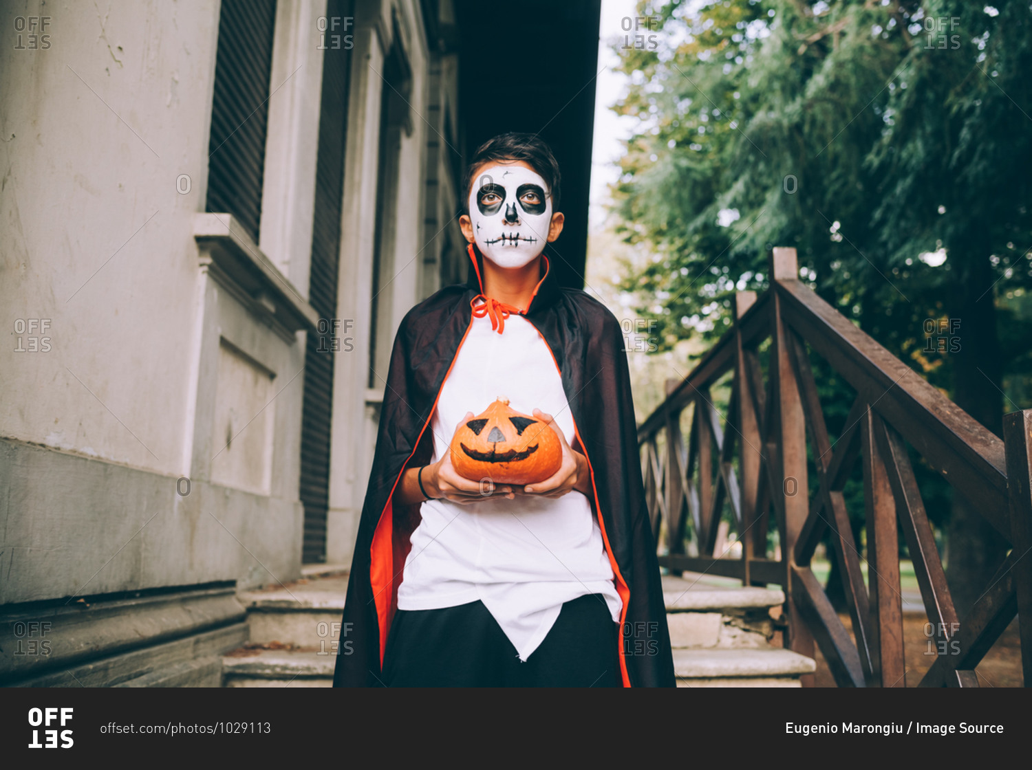 Boy in Halloween costume, holding Jack-O-Lantern