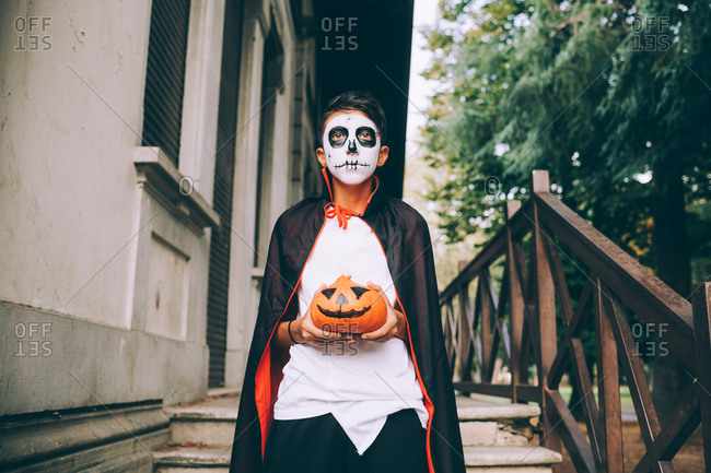 Boy in Halloween costume, holding Jack-O-Lantern