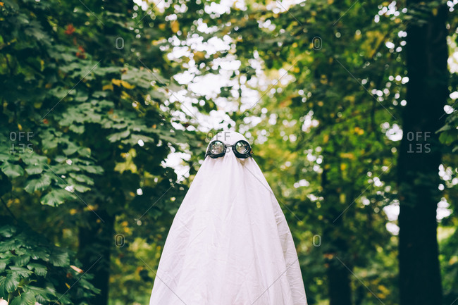 Child in forest wearing ghost Halloween costume