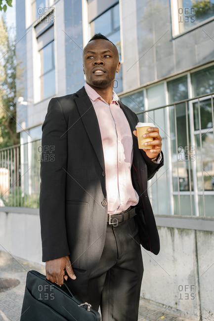 African American businessman walking around the city with his briefcase holding a glass of coffee