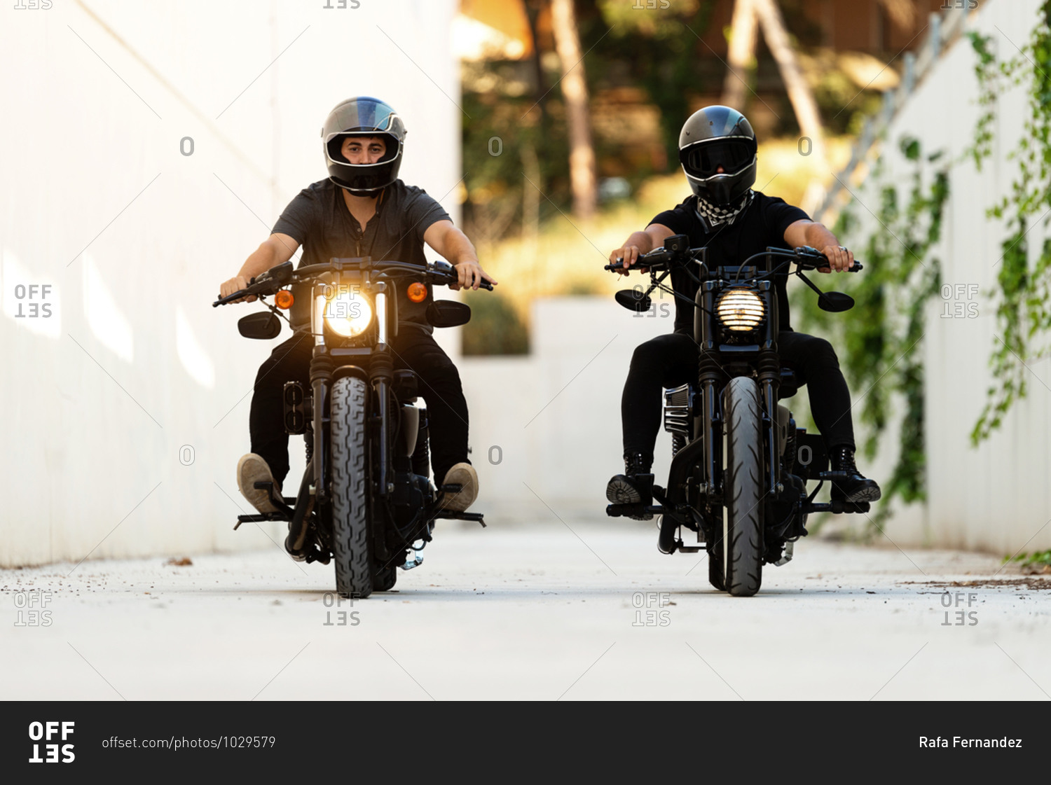 Two bikers riding on cafe racer motorcycles with lights on