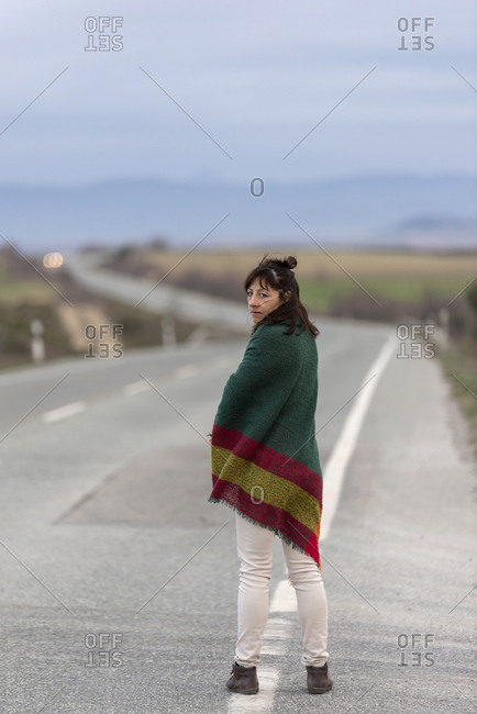 Woman standing on a road, wrapped in a blanket