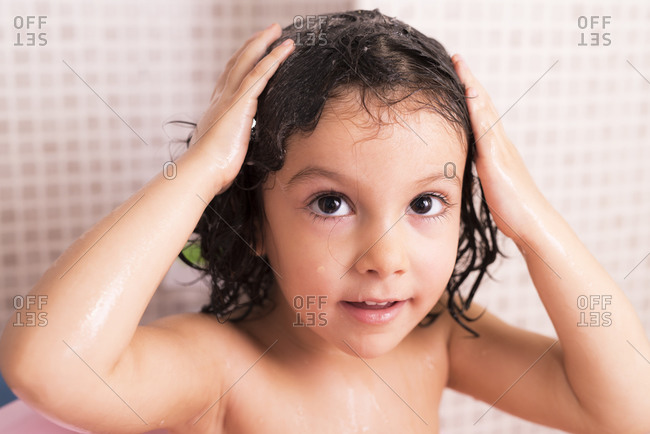 Little three years old girl washing her head and hair