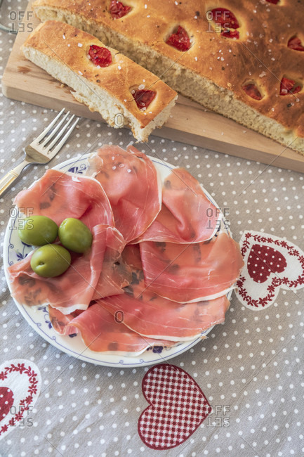 Homemade apulian focaccia served with parma's ham and olives, typical italian food