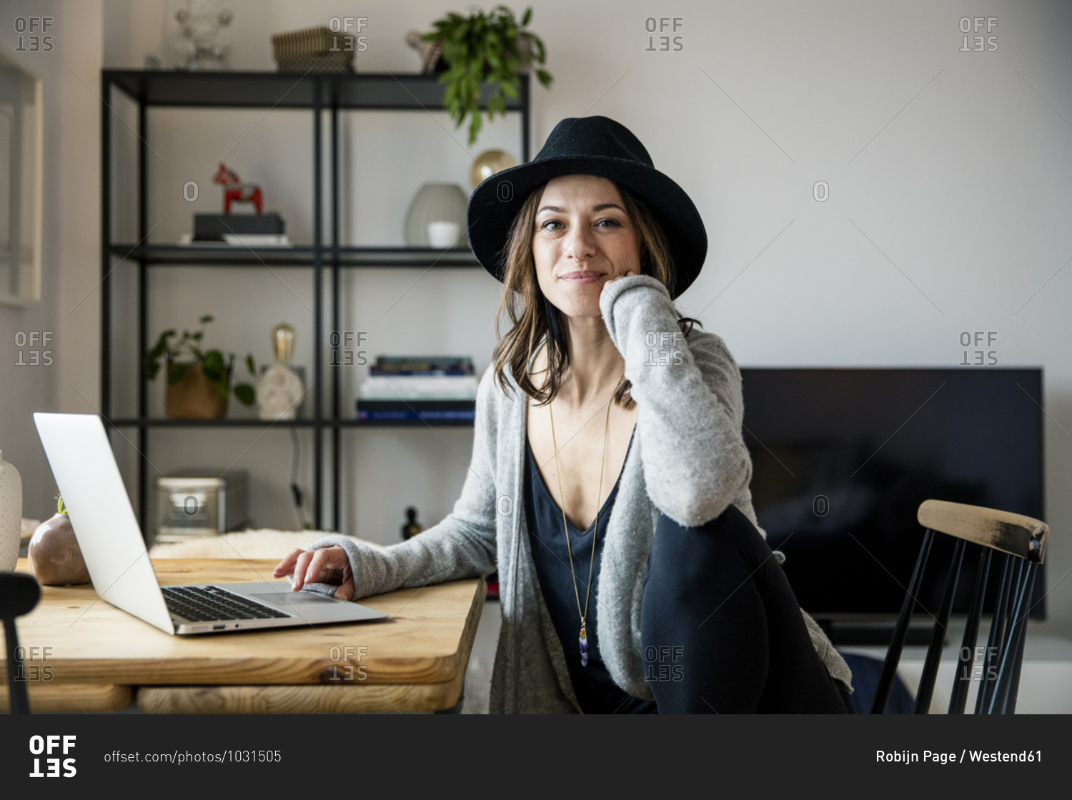mature woman with hat- sitting at home- using laptop