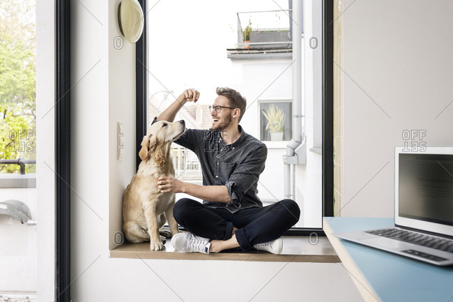 Happy man with dog sitting at the window