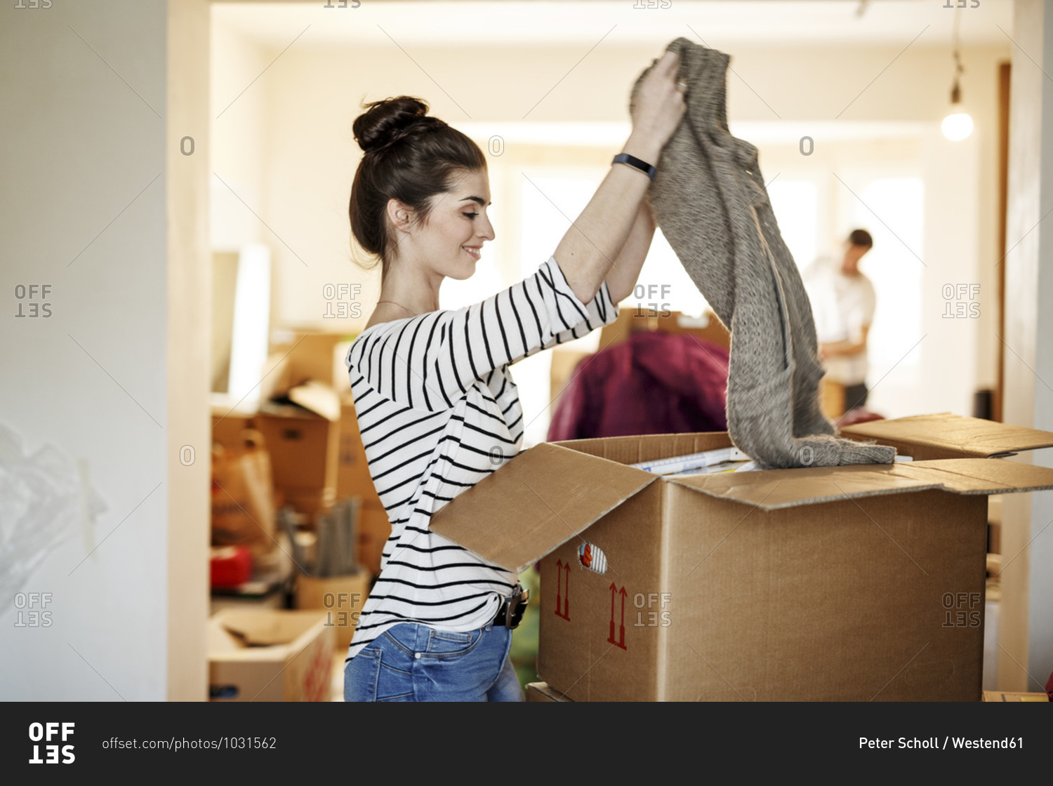Young woman moving house- unpacking cardboard boxes