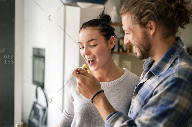 Young couple preparing food together- tasting spaghetti