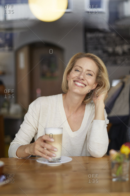 Portrait of happy woman with latte macchiato in a coffee shop