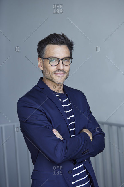 Portrait of stylish businessman with stubble wearing blue suit and glasses