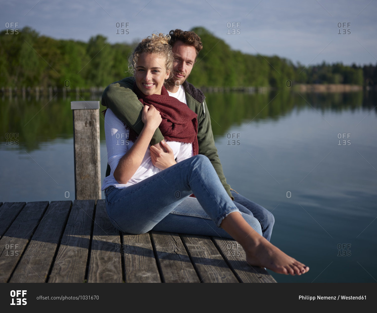Romantic couple sitting on jetty at the lake