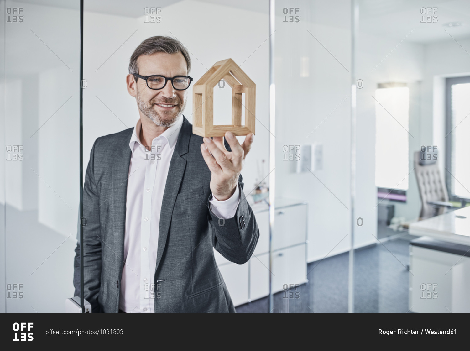 Smiling businessman looking at architectural model in office