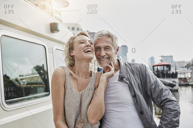 Happy older man and young woman on jetty next to yacht