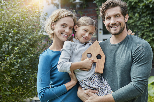 Portrait of happy family in front of their home with house model