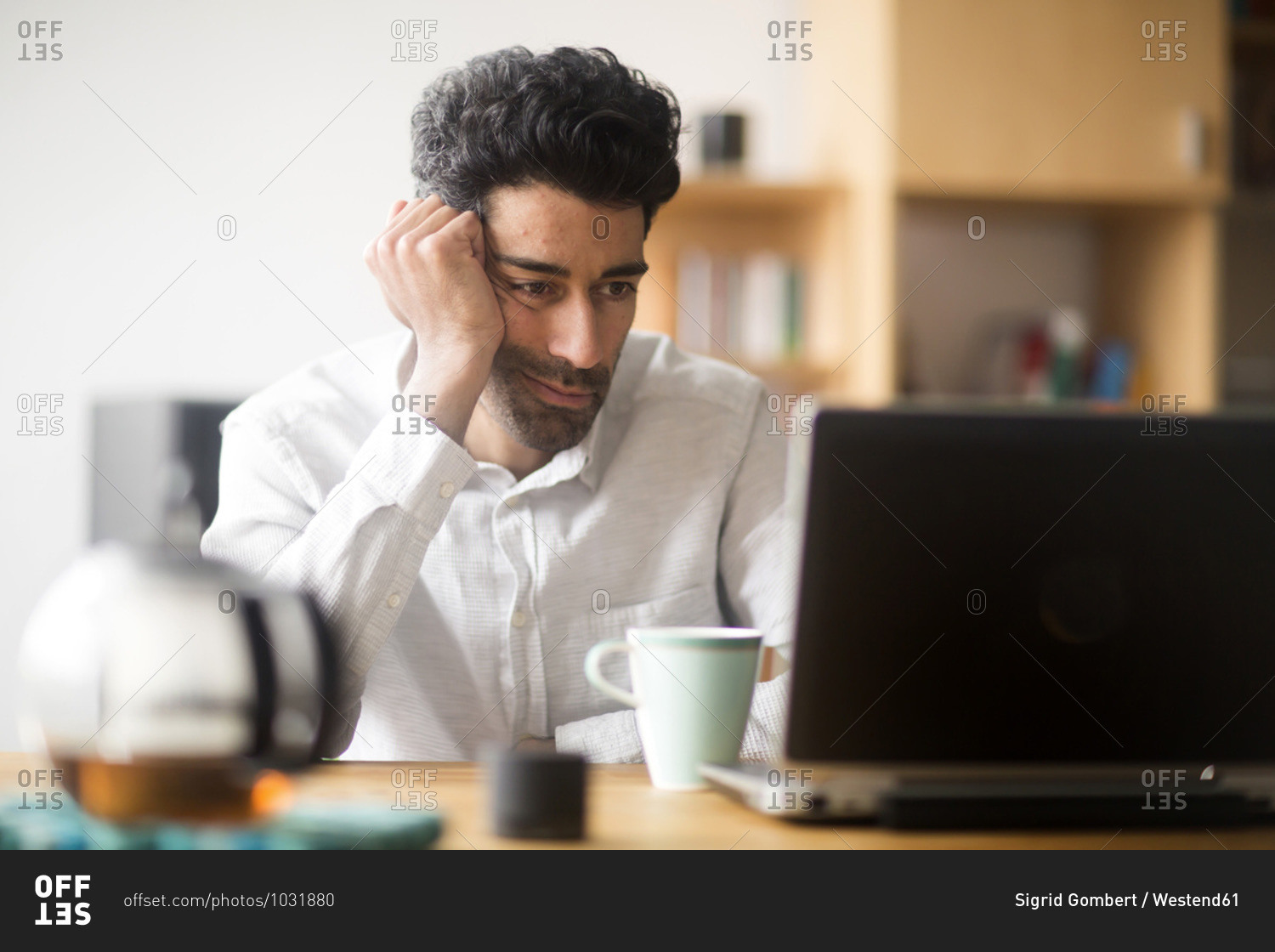 Portrait of businessman at desk looking at laptop