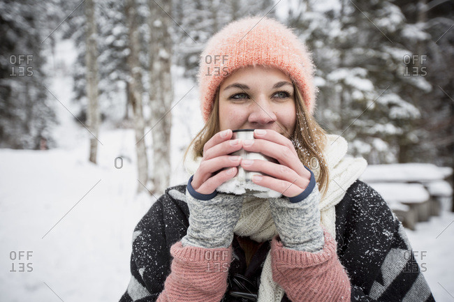 Portrait of young woman drinking hot drink outdoors in winter
