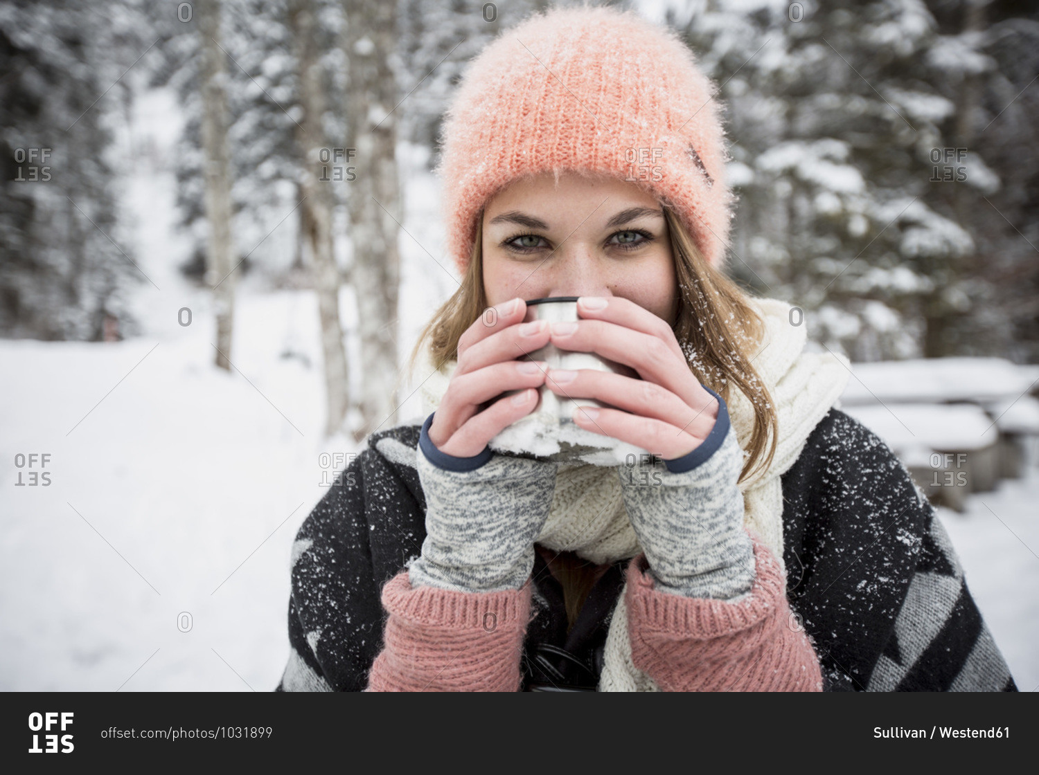 Portrait of young woman drinking hot drink outdoors in winter
