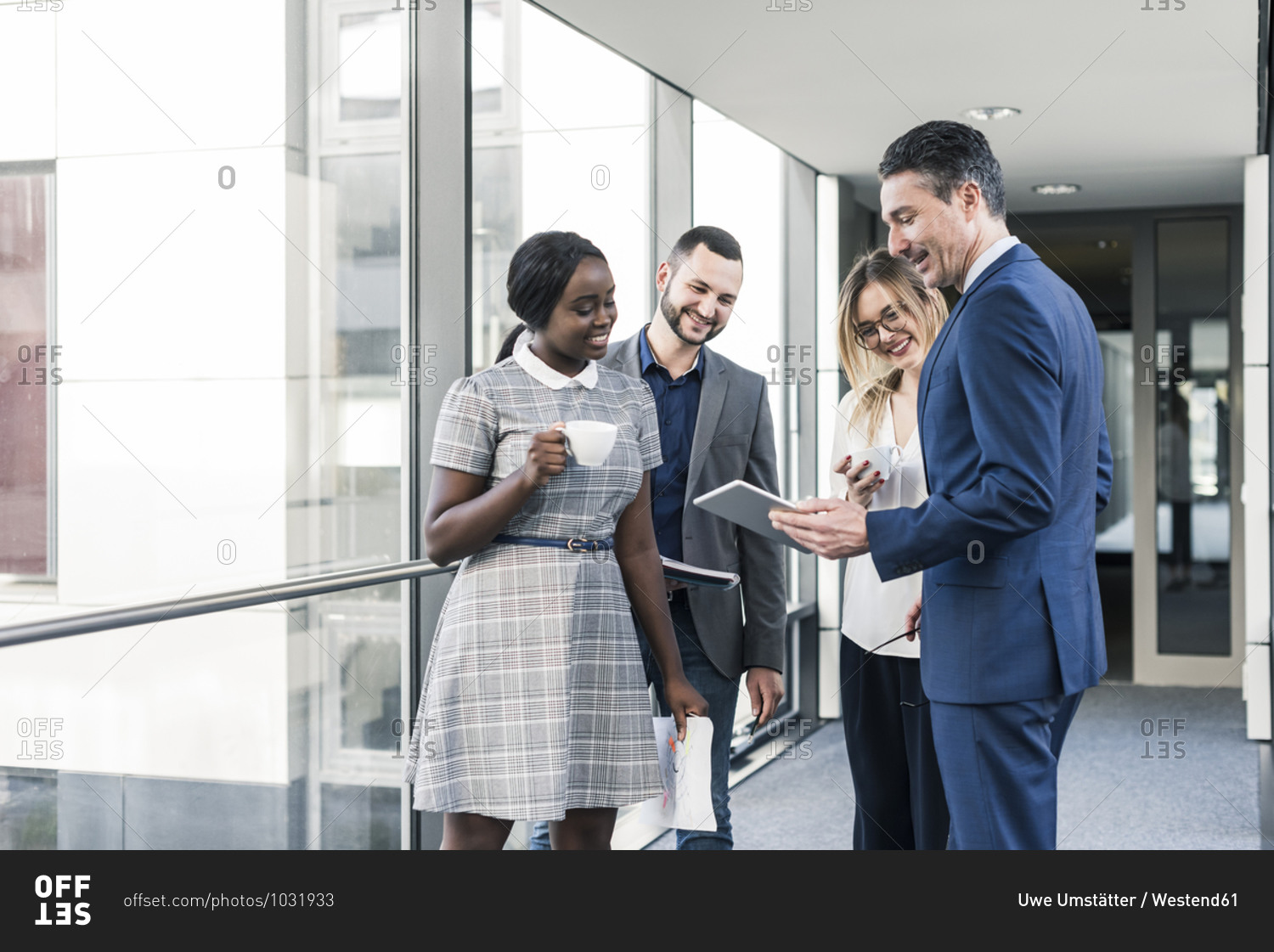 Smiling business people with tablet talking on office floor