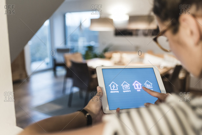 Woman using tablet with smart home control functions at home