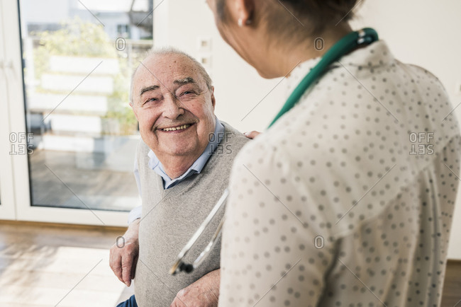 Senior man smiling at nurse at home