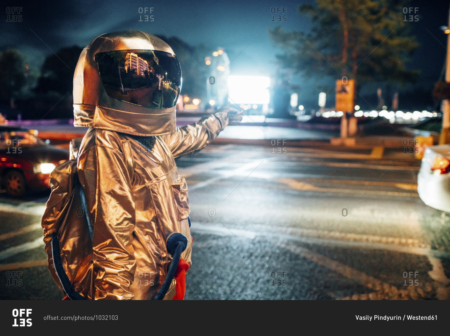 Spaceman on a street in the city at night pointing at shining projection screen