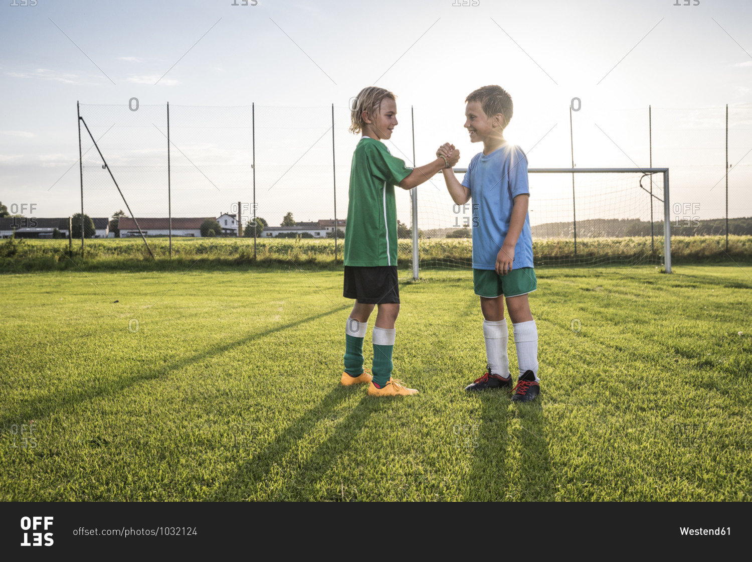 Smiling young football players shaking hands on football ground