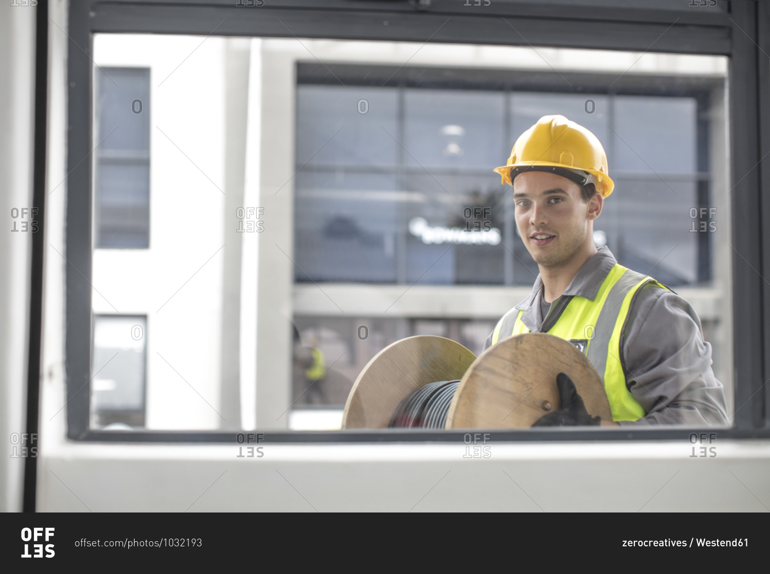 Portrait of construction worker carrying cable drum