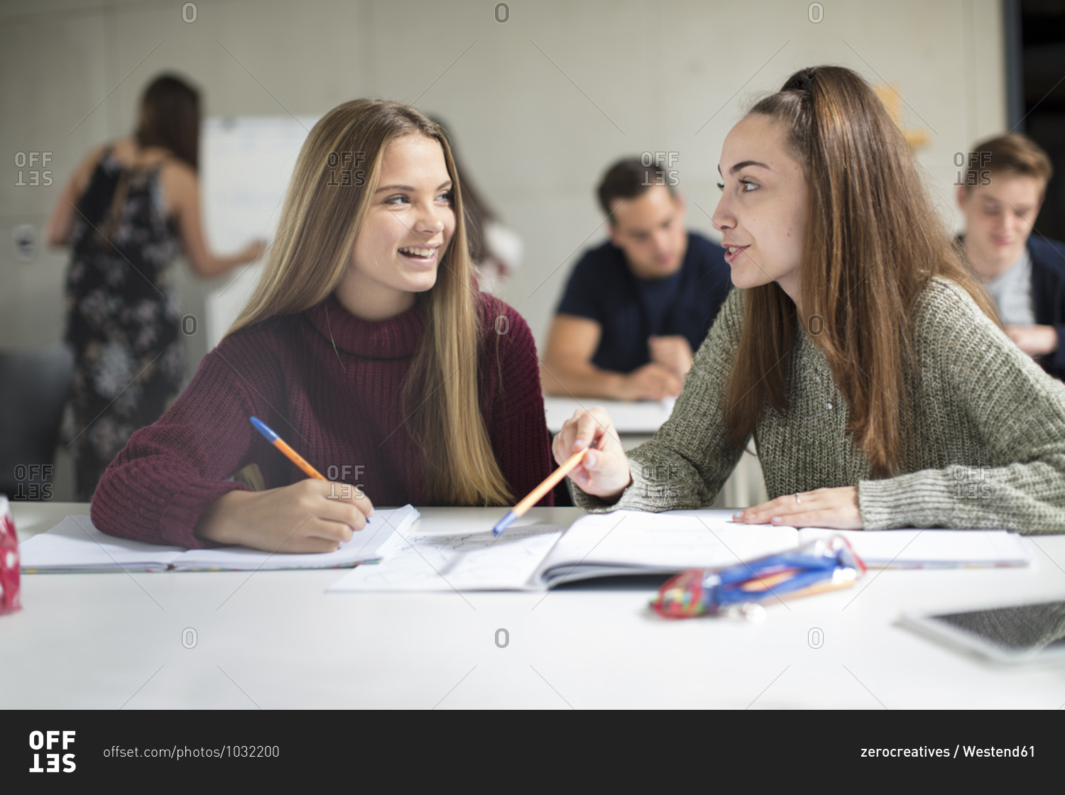 Smiling teenage girls talking in class