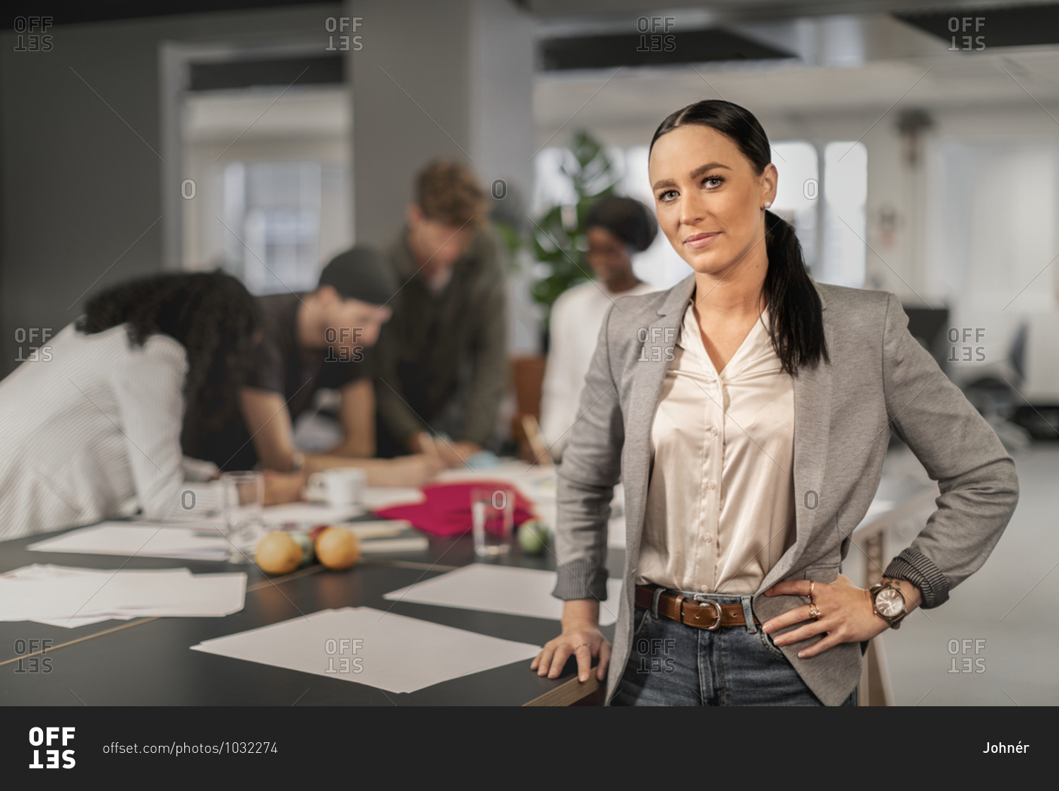 Woman looking at camera, coworkers at meeting on background