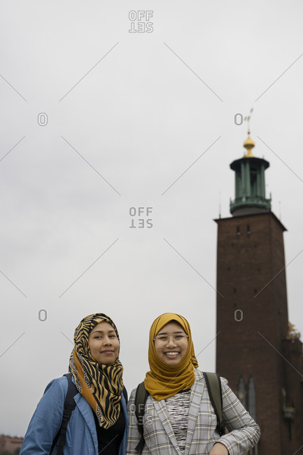 Female friends looking at camera, Stockholm City Hall on background, Stockholm, Sweden