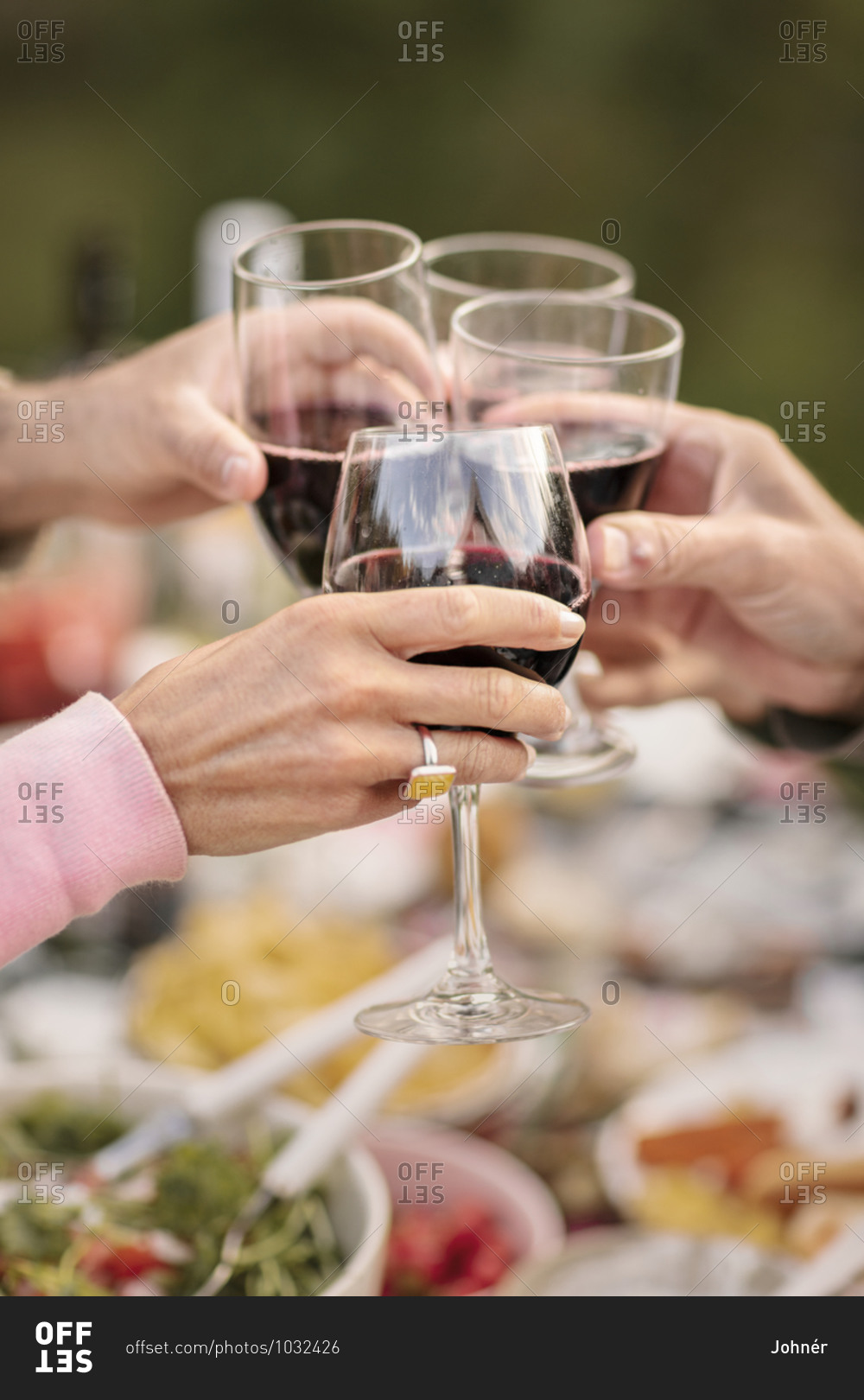People clinking red wine glasses
