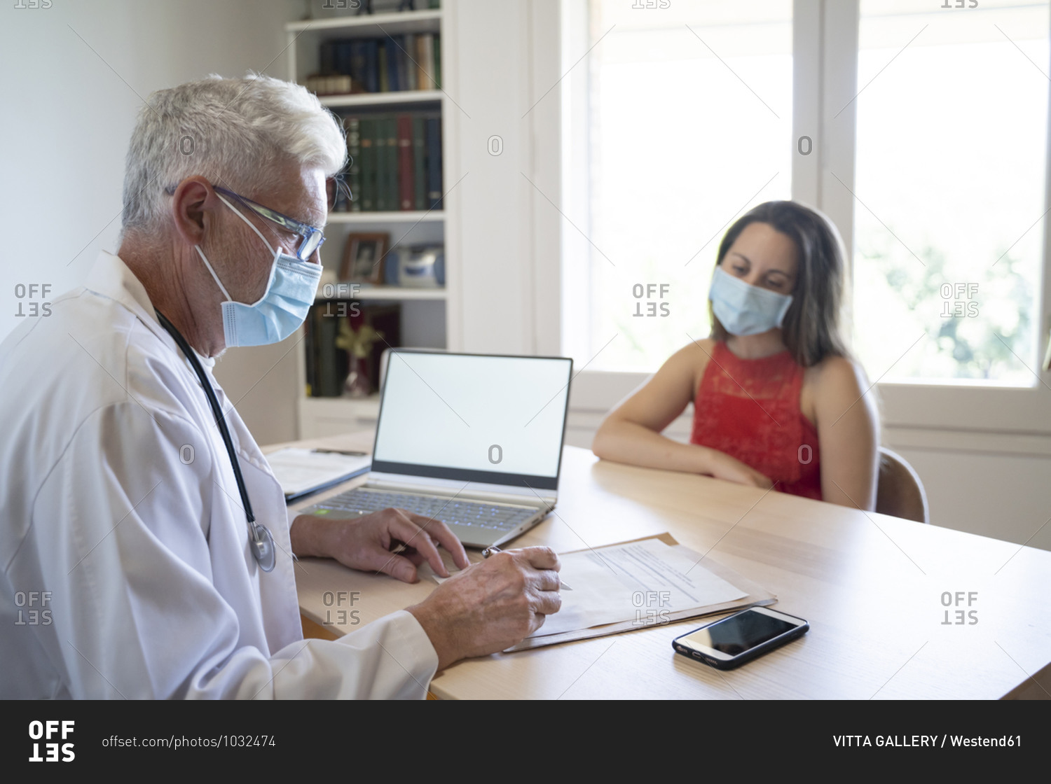 Doctor examining medical record of patient while sitting in clinic