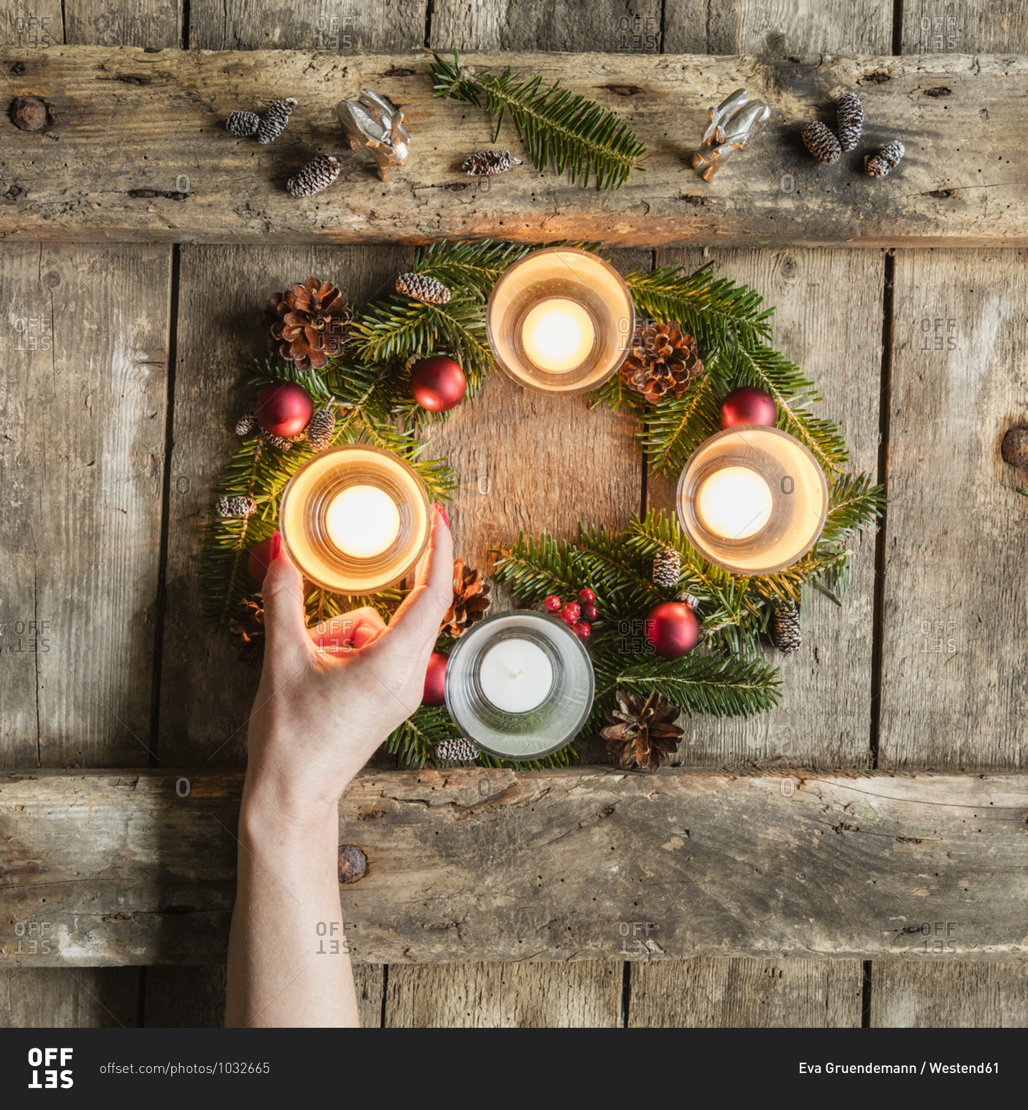 Hand of woman touching glass cover of candle burning on Advent wreath