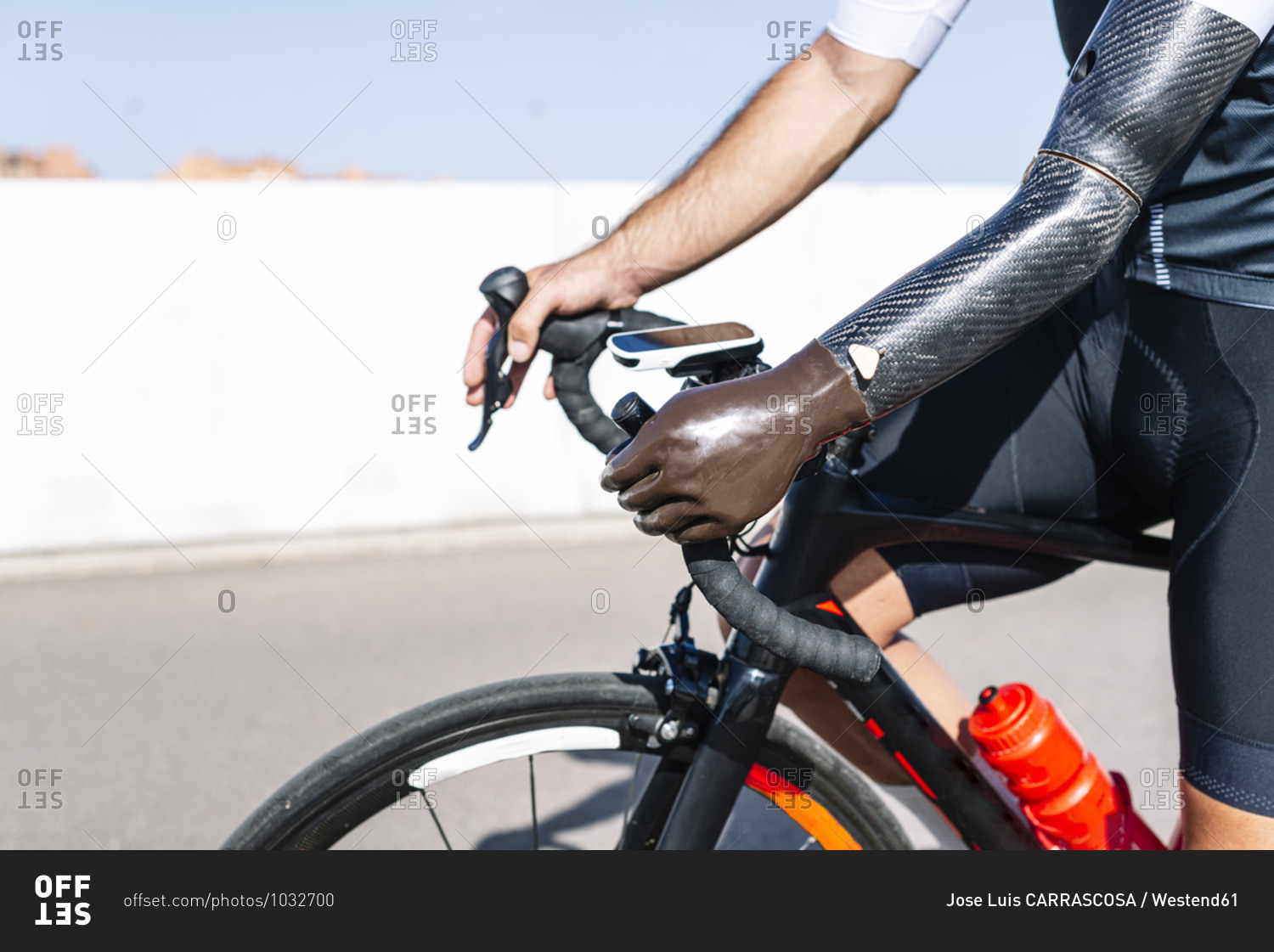 Close-up of male amputee athlete with artificial hand riding bicycle on road