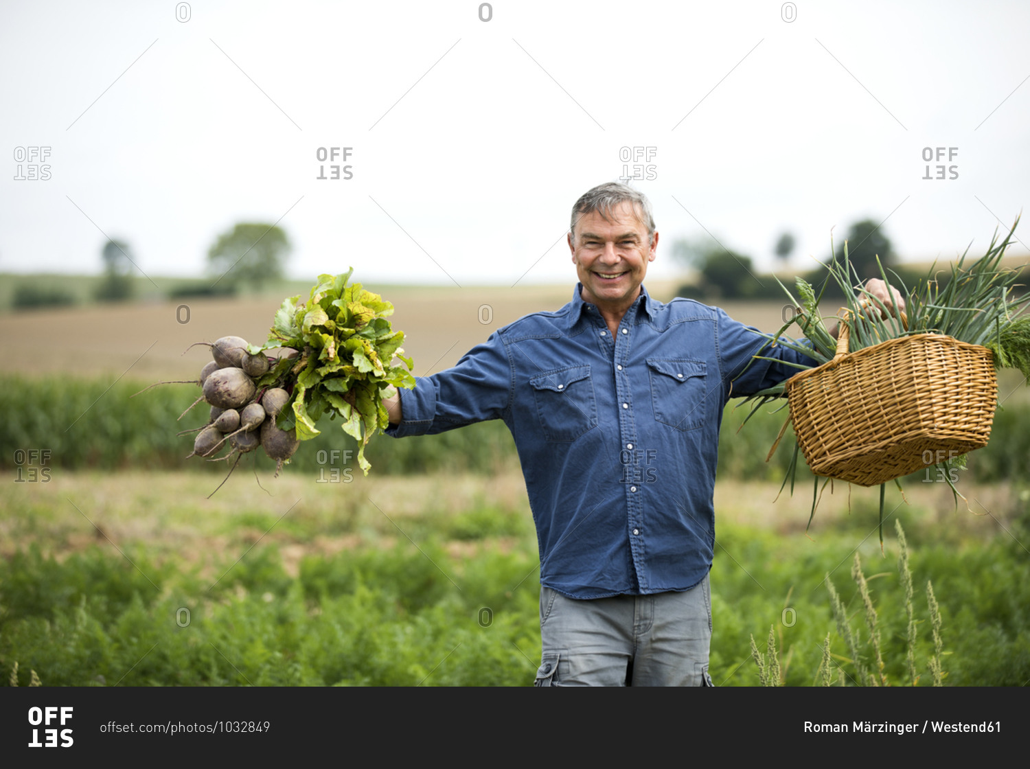 Man smiling while holding vegetables in both the hands at farm