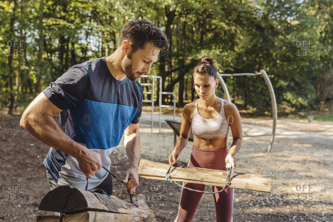 Woman and man lifting up heavy logs on a fitness trail